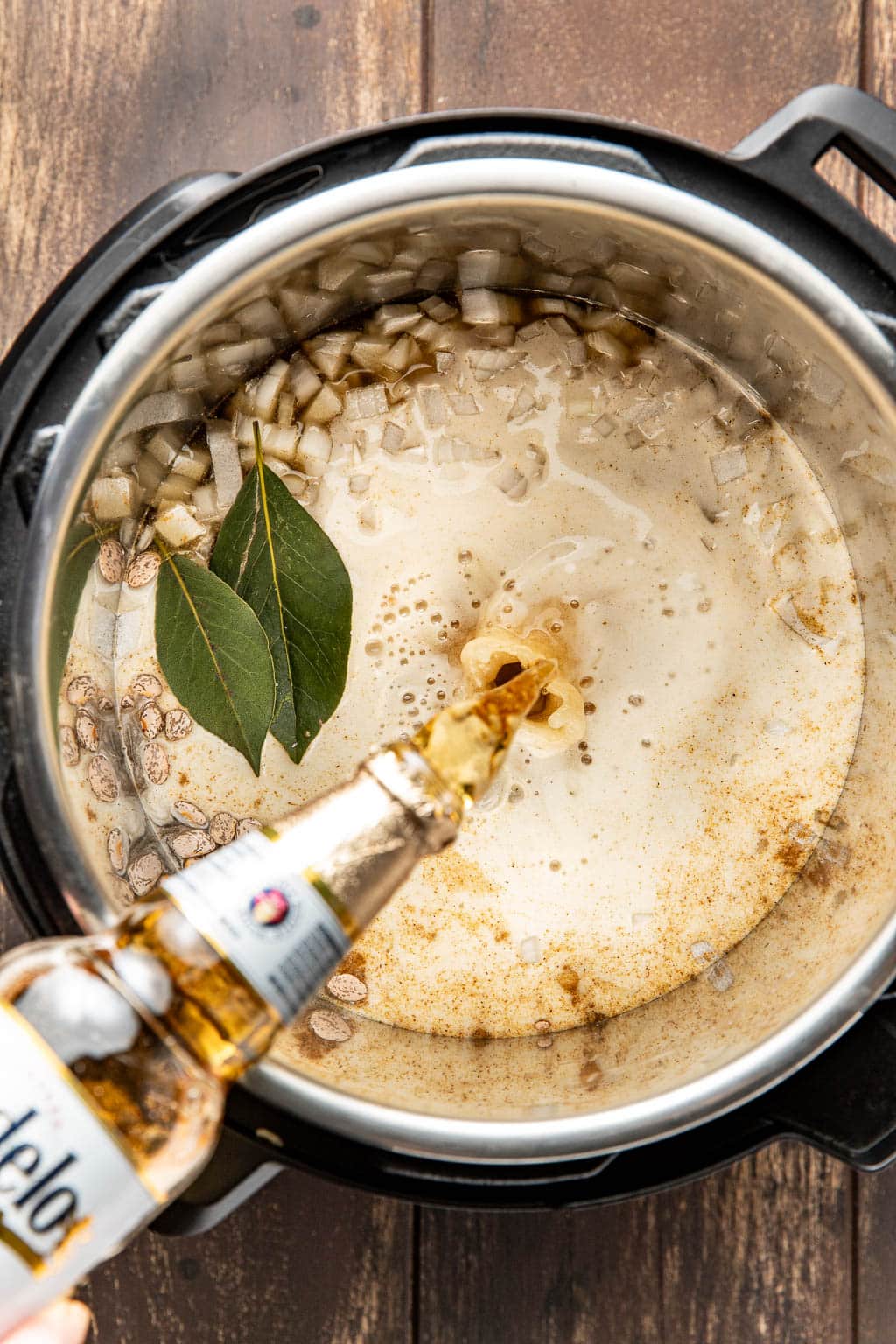 Beer being poured into the instant pot with the beans before cooking