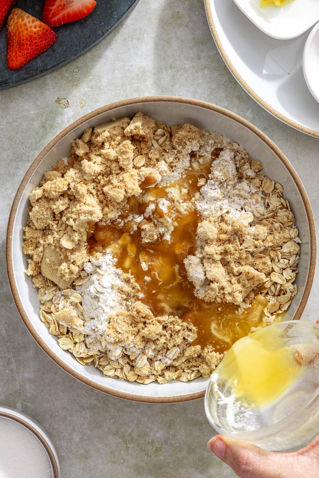 Butter being poured over oats, sugar, and flour to make the crisp topping.