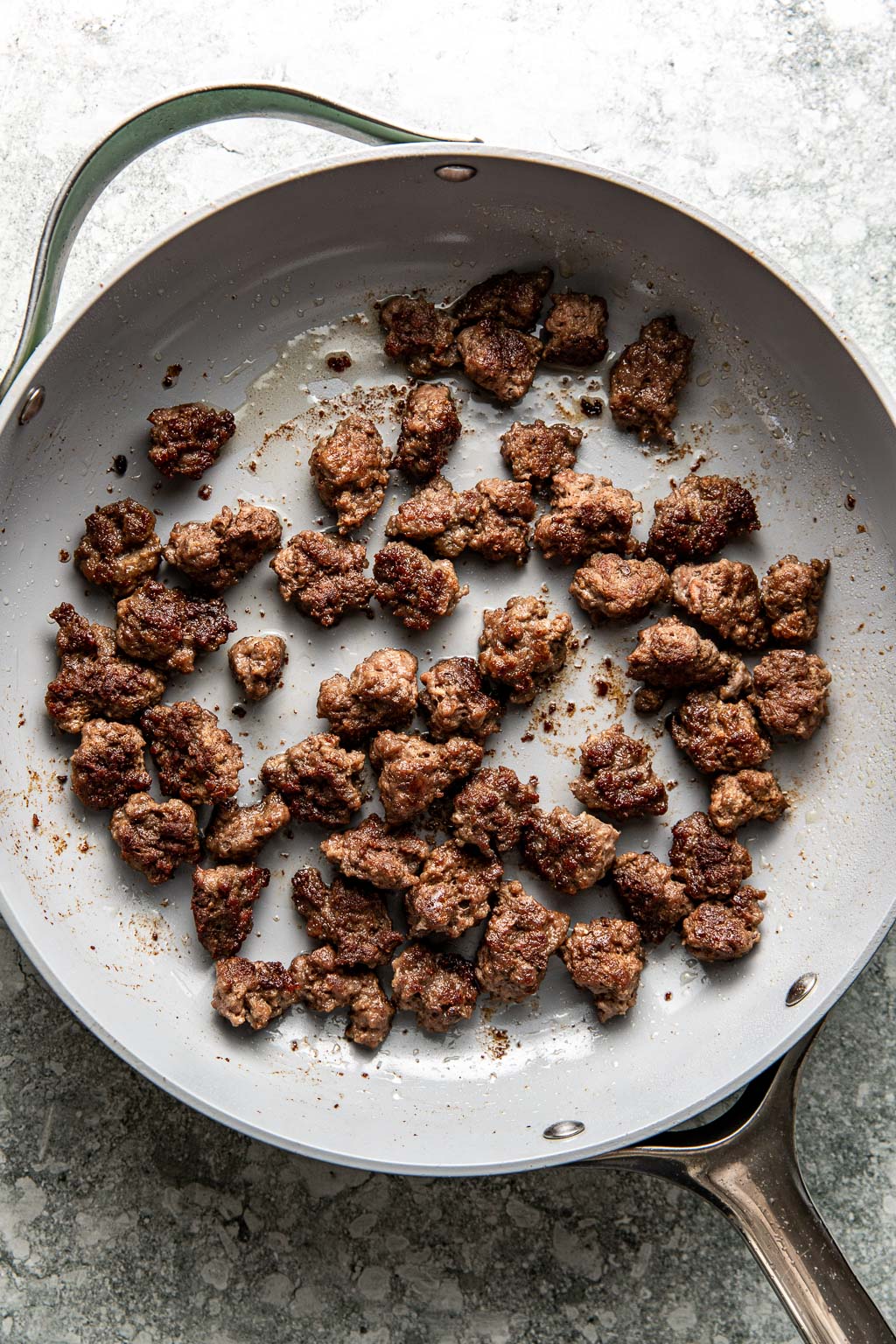 Ground beef pieces in a skillet after being browned
