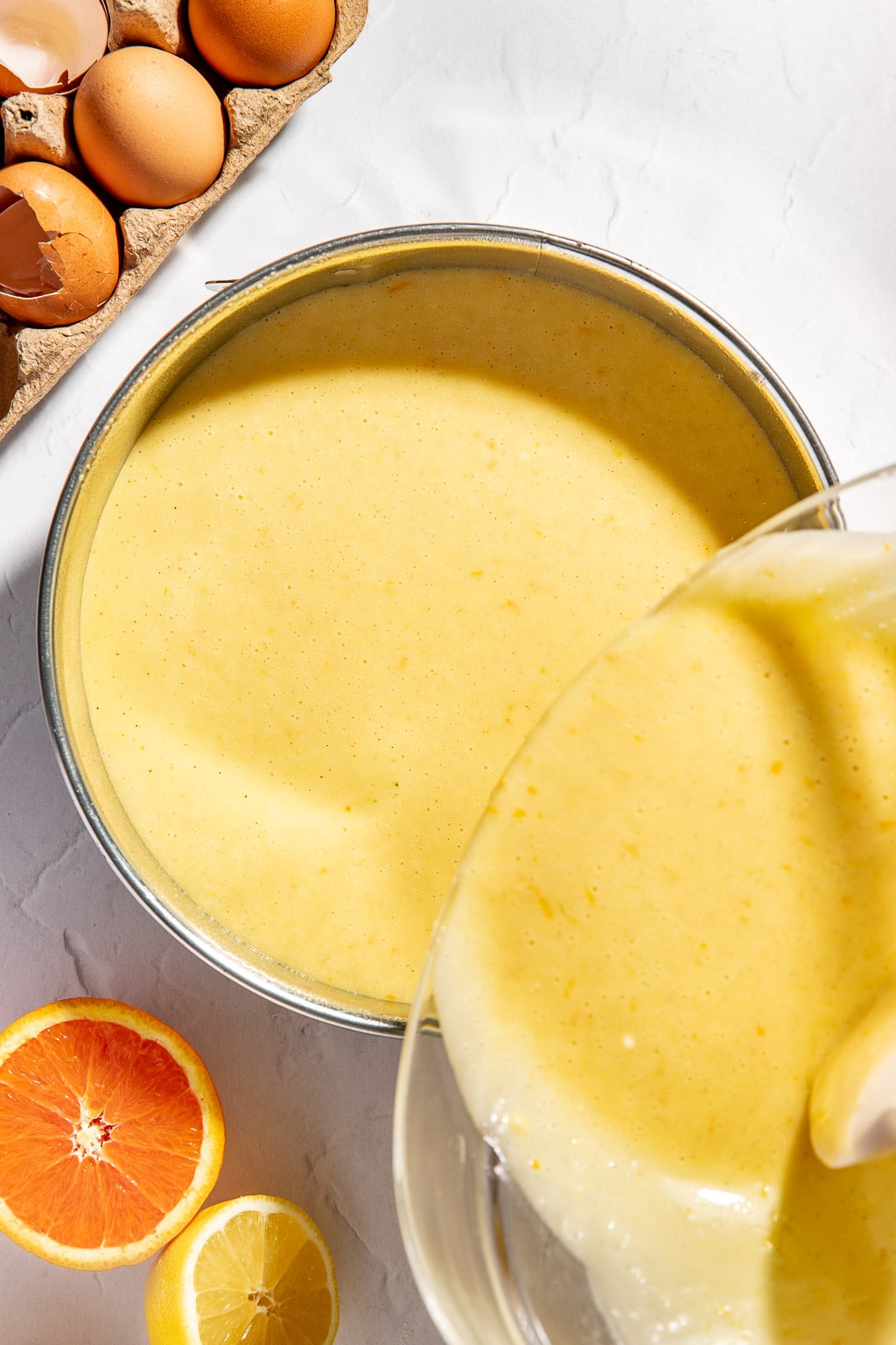olive oil cake batter being poured into a cake pan