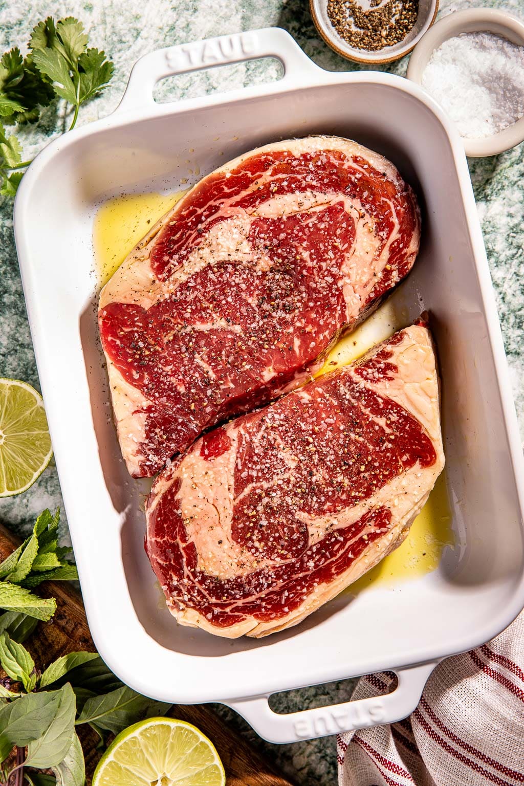 seasoned steaks in a baking dish before grilling