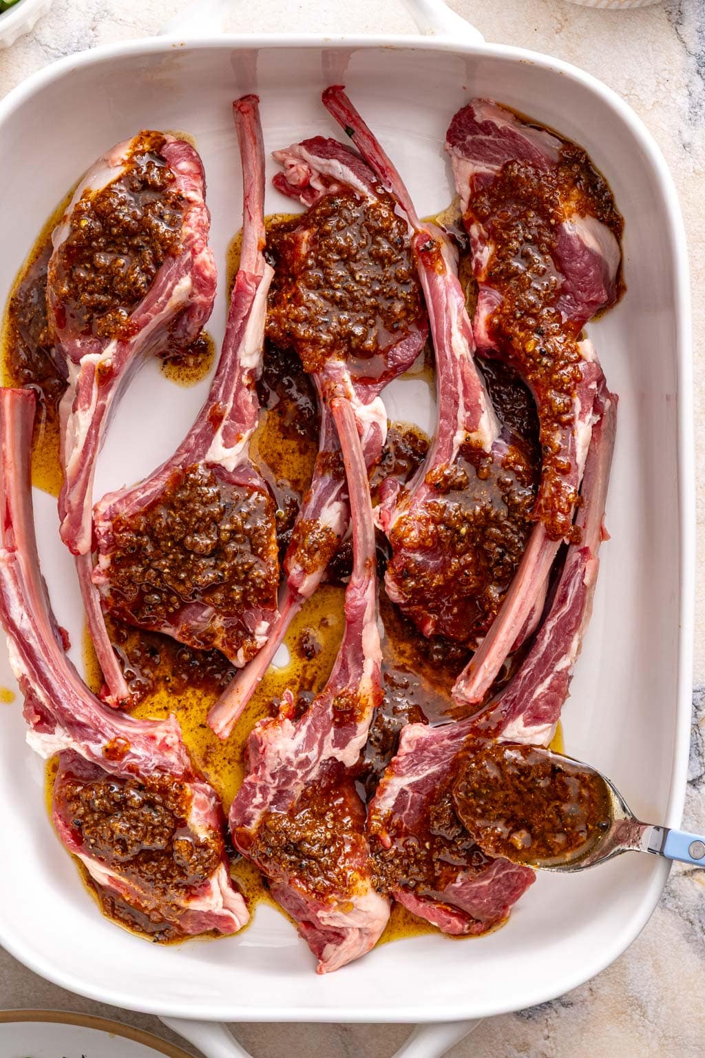 lamb chops in a baking dish with the marinade on top