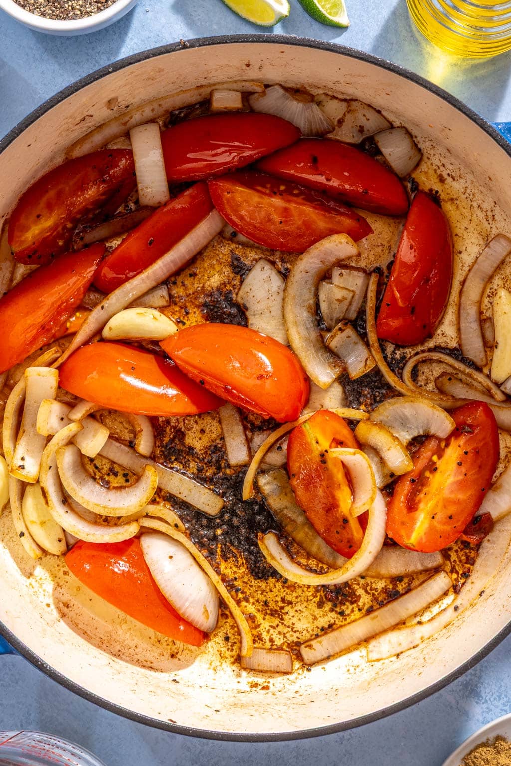 Tomato, onion, and garlic being cooked in a dutch oven