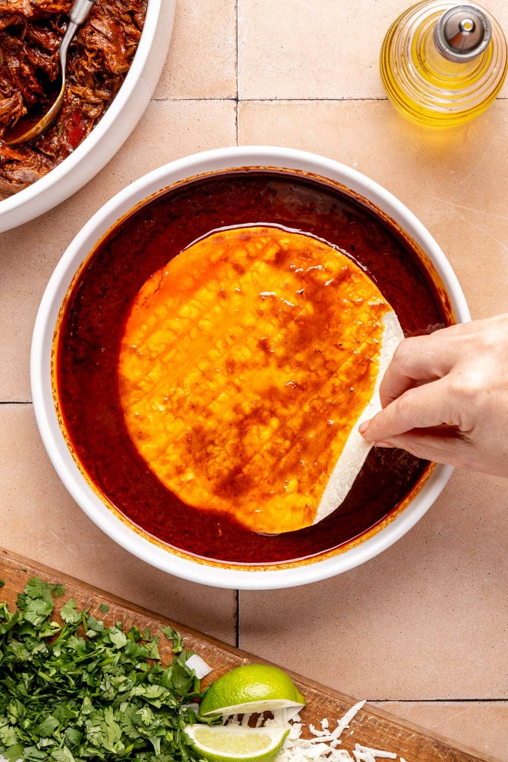 a corn tortilla being dipped in birria fat/broth