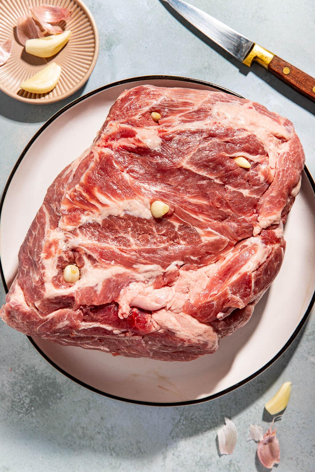 garlic cloves being inserted into the pork shoulder