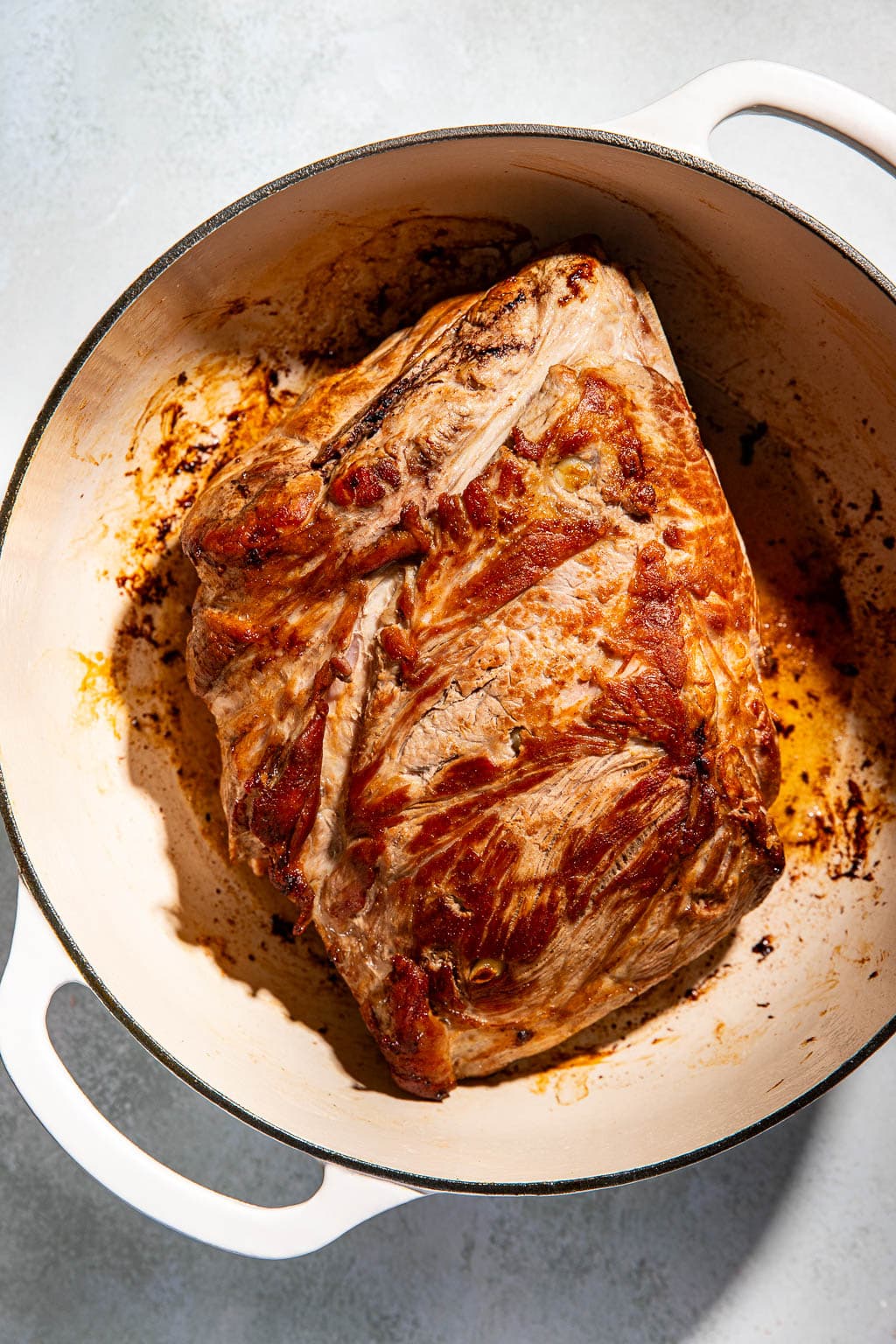 pork shoulder being seared in a dutch oven