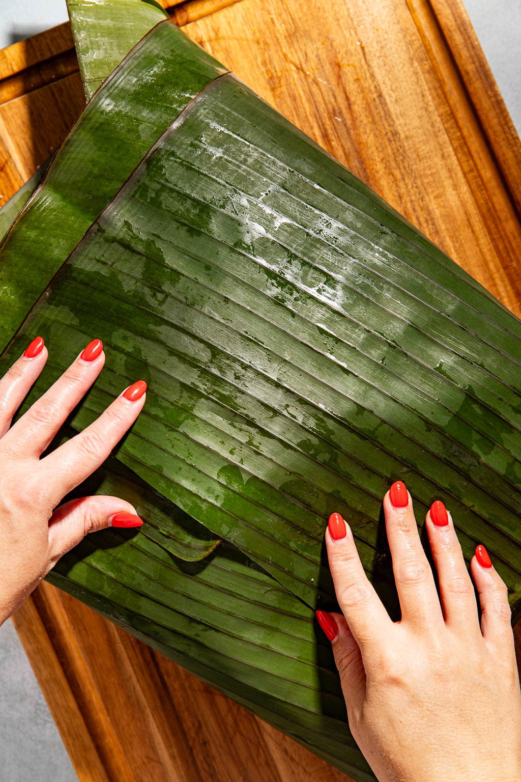 pork being wrapped in banana leaves