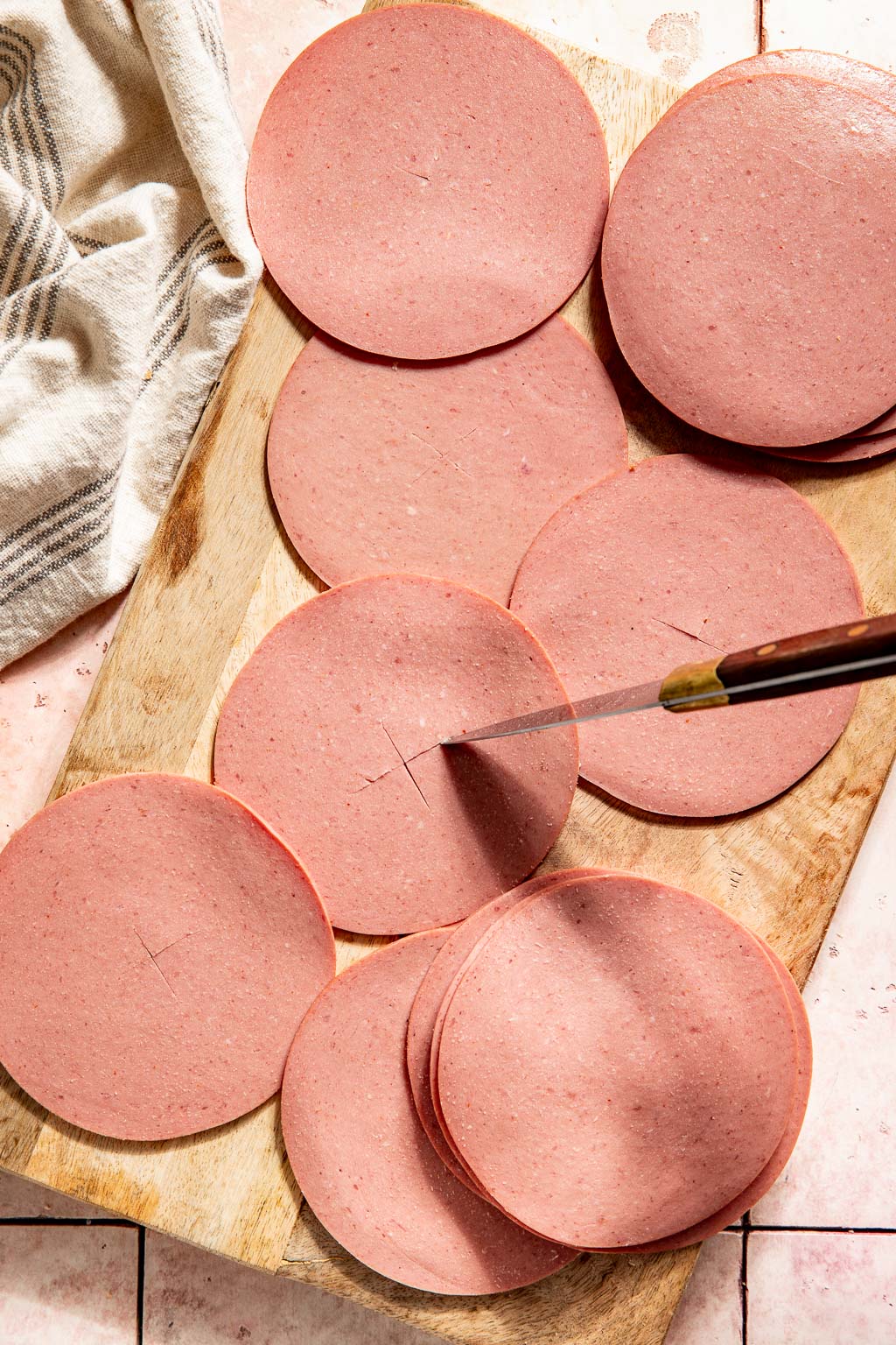 an 'x' being cut into the center of a slice of bologna