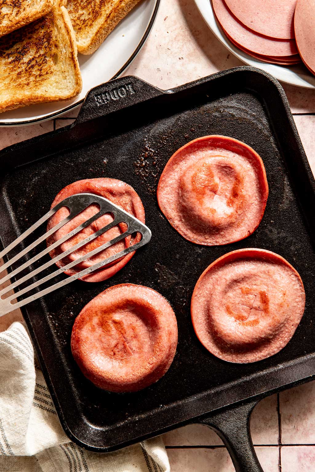 bologna being cooked on a griddle