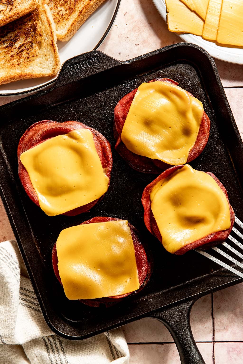 cheese being melted on the fried bologna