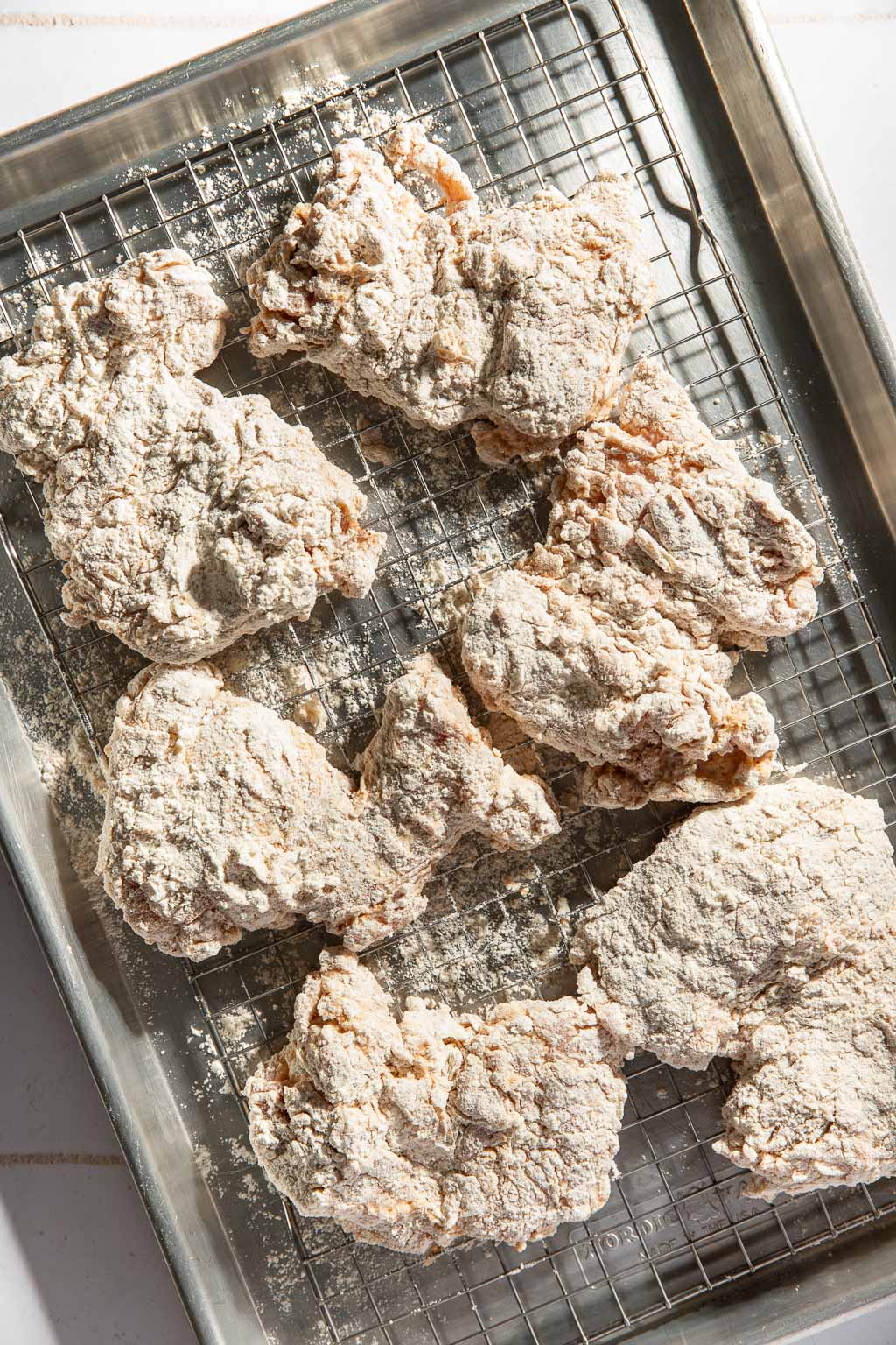 dredged chicken on a baking sheet before frying