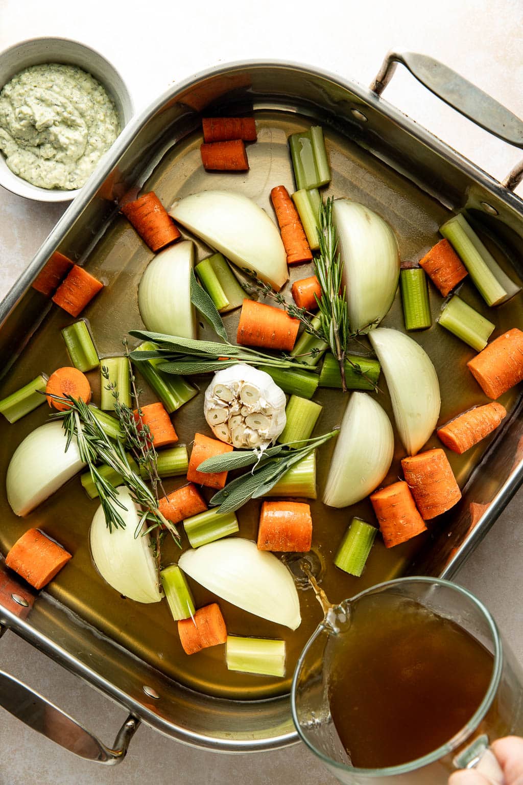 pouring turkey stock into roasting pan with vegetables 