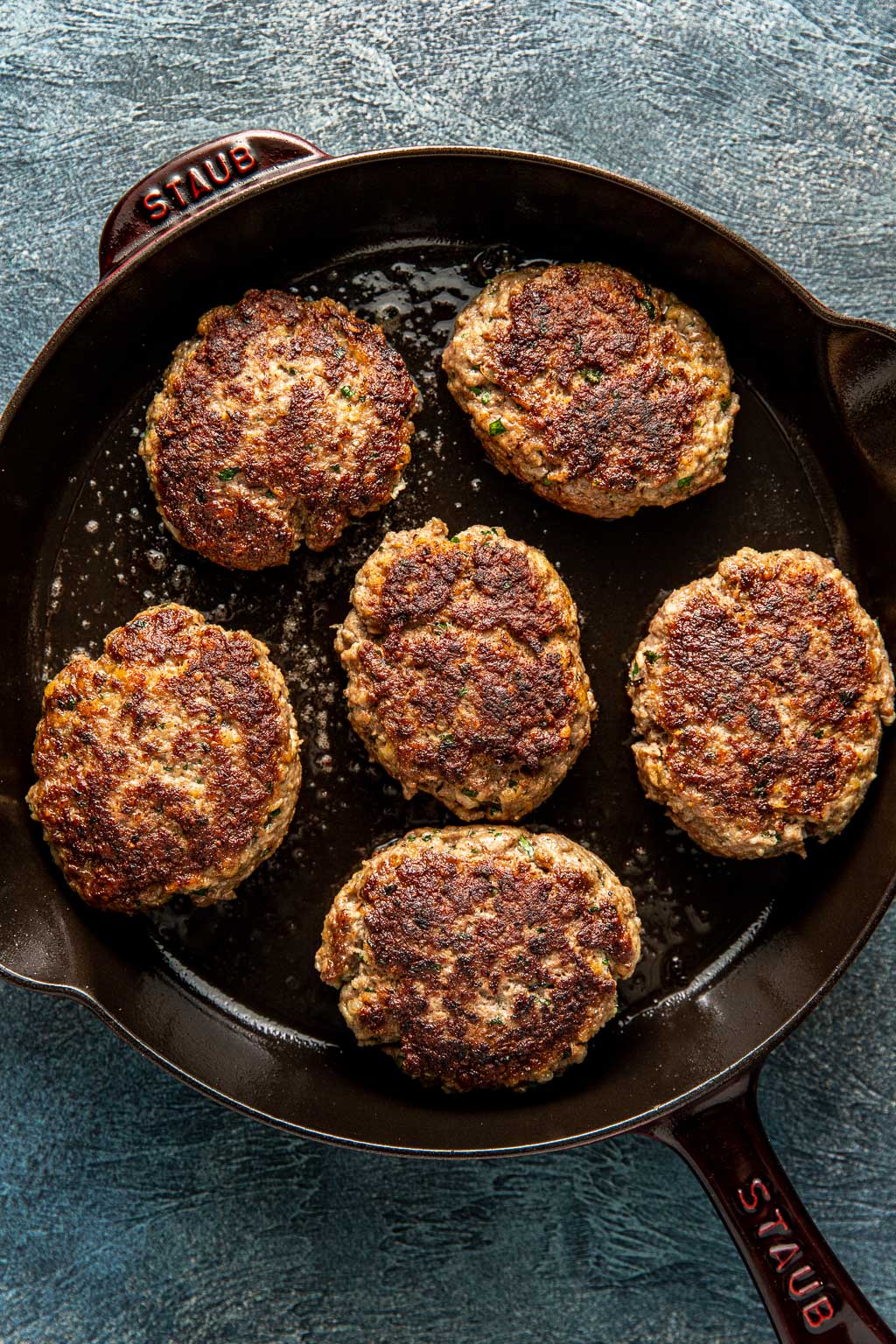 Salisbury steak patties searing in a cast iron skillet