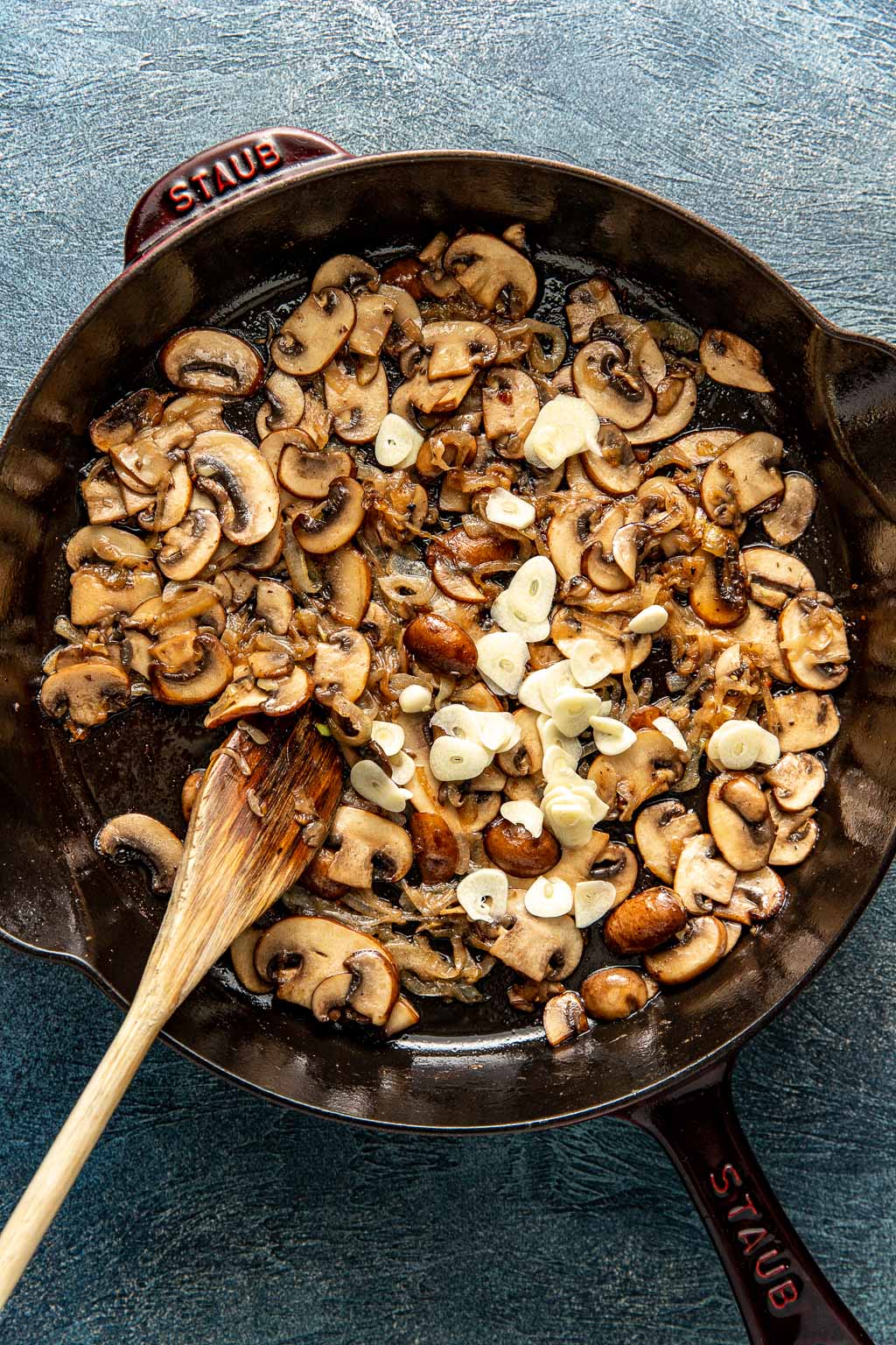 mushrooms onions an garlic in a skillet being sautéed